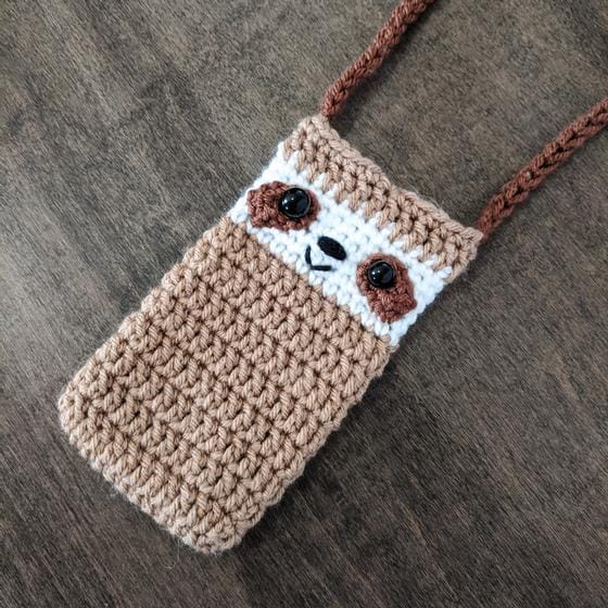 A crocheted sloth phone holder