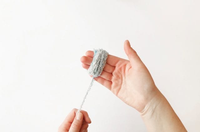 Wrapping fur yarn around your hand to make a DIY pom-pom
