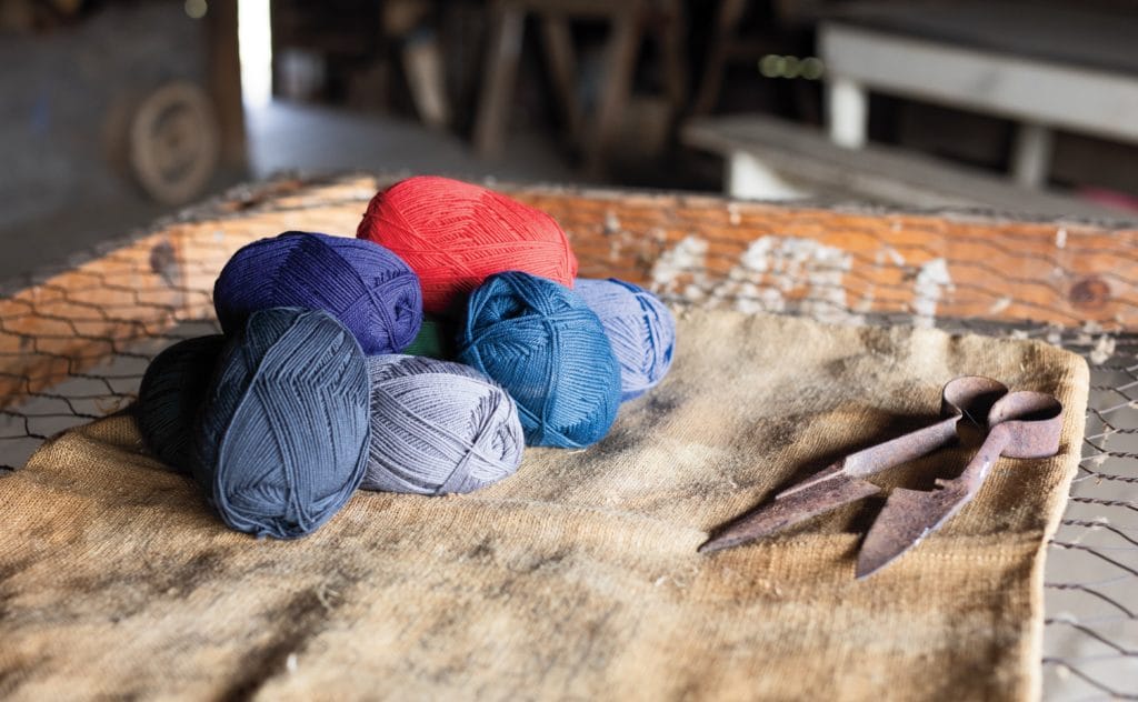 Assorted High Desert yarn balls sit on a piece of old cloth near a set of vintage shearing clippers